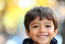 12 Consejos para Criar Niños Seguros de Sí Mismos Niño sonriente con chaqueta azul y fondo desenfocado; ideal para ilustrar temas relacionados con "Criar Niños Seguros" o fomentar la autoestima y la felicidad en la infancia.