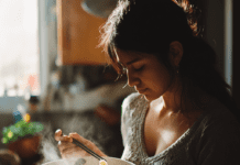 Pho para Hispanos Mujer hispana sosteniendo un tazón humeante de Pho para Hispanos, mezclando fideos de arroz y cilantro en una cocina iluminada.